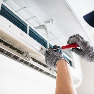Technician repairing an air conditioner with a screwdriver.