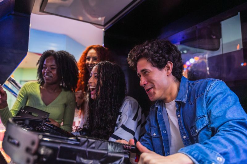 Group of friends having fun playing on a retro arcade machine in an amusement arcade or bowling alley
