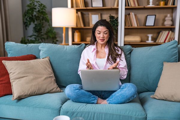 Woman video conferencing on a laptop from her couch.