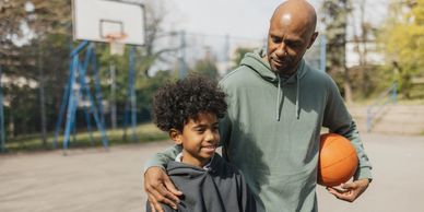 Man and boy with basketball on outdoor court.