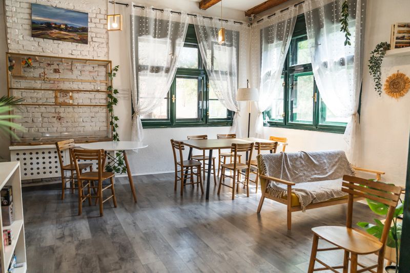 Empty modern café interior with wooden furniture, white brick walls, and large windows, creating a bright and welcoming atmosphere