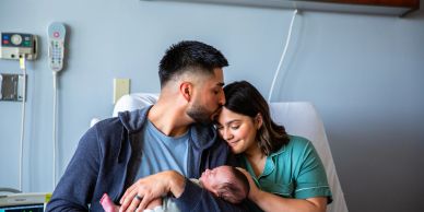 New parents lovingly cradle their newborn in a hospital room.