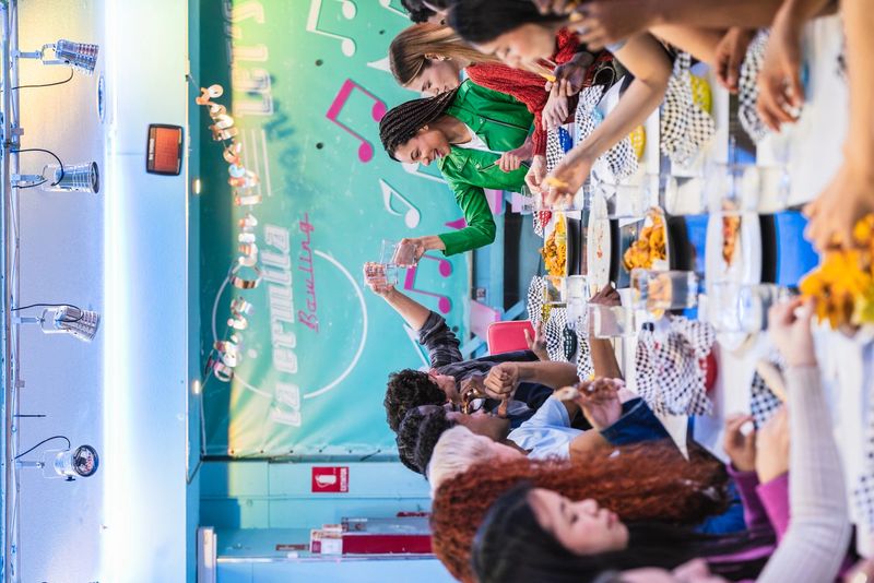 Cheerful friends sharing a meal and drinks at a bowling alley restaurant, celebrating friendship and good times