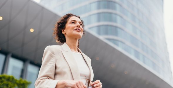 Confident businesswoman standing outdoors near a modern office building.