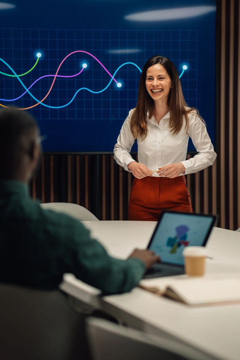 Businesswoman leading a meeting and presenting growth data on a graph in a modern office