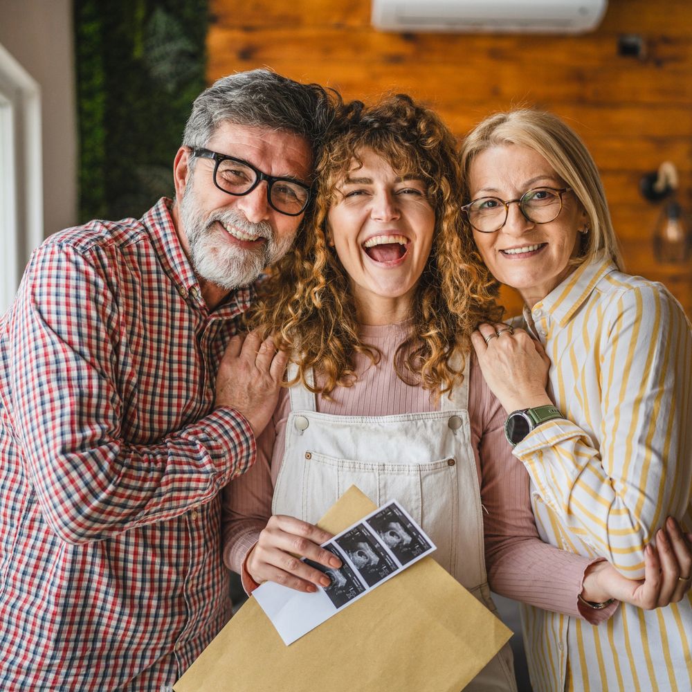 Happy family celebrating with ultrasound photos, expecting a baby.