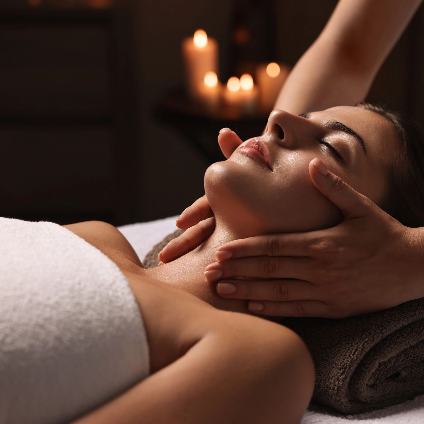 Woman enjoying a relaxing facial massage in a dimly lit spa.