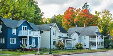 A row of colorful houses along a street with fall foliage.