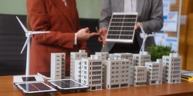 Two people discussing renewable energy with solar panel and wind turbine models.