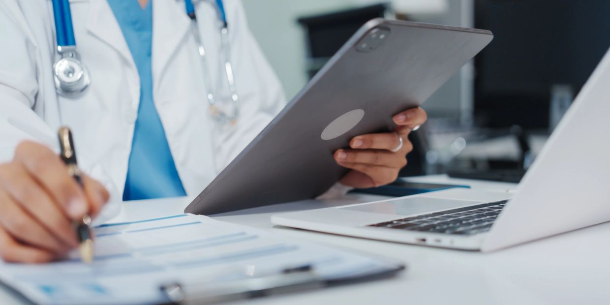 Doctor using tablet and making notes.