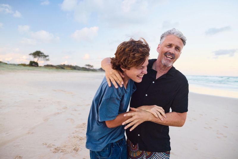 Father and teenage son share a playful moment on a beautiful beach in australia, celebrating family and connection