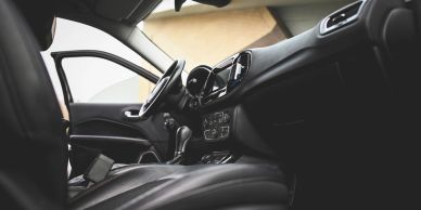 Interior view of a modern car with open door and black leather seats.