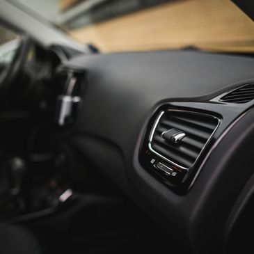 Close-up of a car's air vent and dashboard interior with sleek black design.
