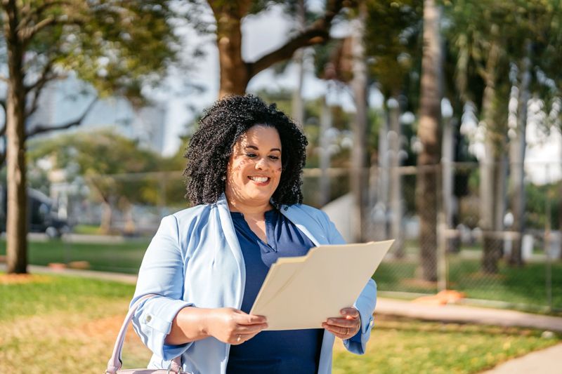 Mid-adult plus size African-American businesswoman holding documents and paperwork on the street in downtown Miami.