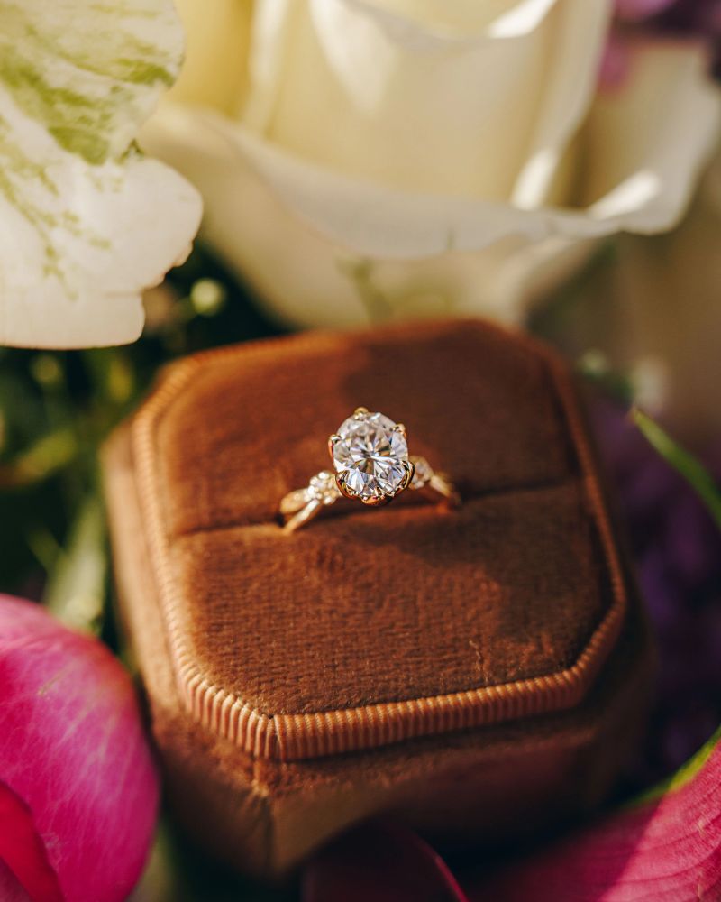 A Diamond engagement ring in velvet box surrounded by vivid florals