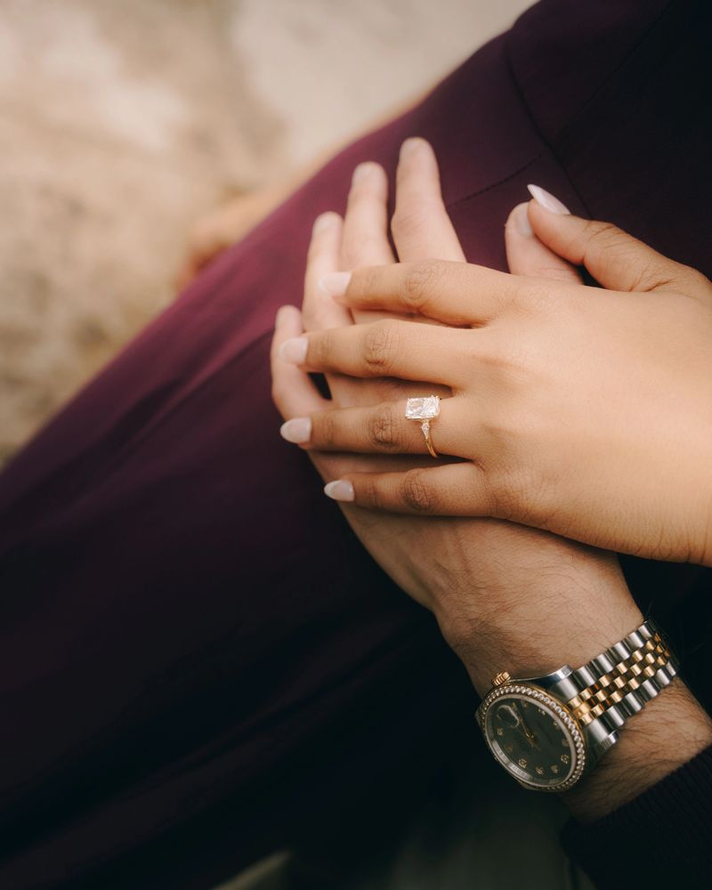 A Close up of an engagement ring on a woman hand resting on her lap outdoors
