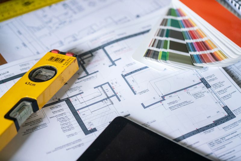 Architectural design layout featuring building plans, a measuring level, and a color palette conveying construction and interior design concepts.