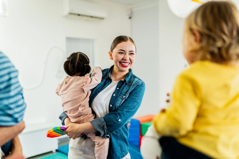 Young mother carrying baby daughter and talking to other parents at parents support group