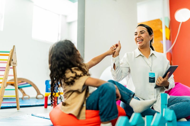 Child boy playing with cubes and talking to therapist during therapy at clinic