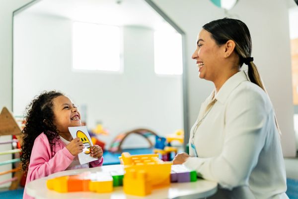 A child and therapist smiling together during a playful therapy session.