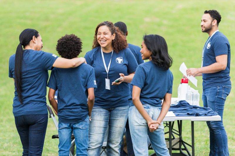 Diverse group of smiling volunteers working together outdoors.  Community event.