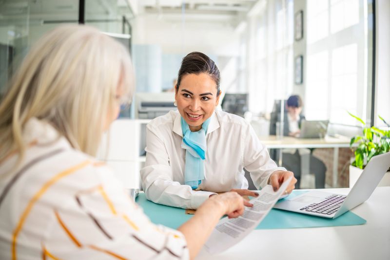 A bank manager engaging with a customer, reviewing documents related to financial planning and investments at a contemporary bank office. The interaction emphasizes trust and professionalism.