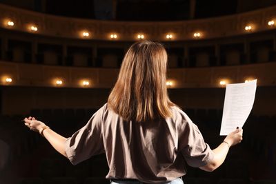 Person rehearsing on an empty theater stage.