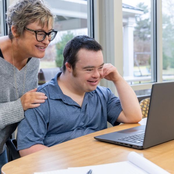 An older woman and a man with down syndrome looking gleefully at a computer screen