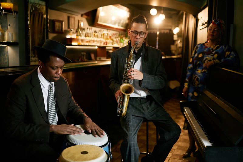 Duet of conga drummer and saxophonist improvising on instruments during jam session during jazz band performance in bar