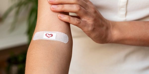 Person placing a heart-printed adhesive bandage on their arm after checking hormone labs in owasso