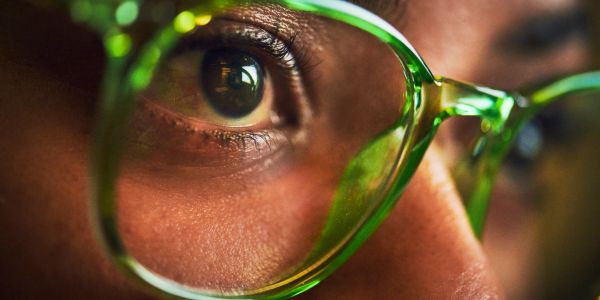 Close-up of an eye behind green glasses.