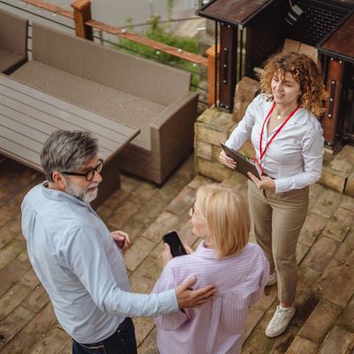 Real estate agent showing a property to a couple outdoors.