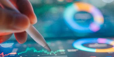 Hand using stylus on digital financial charts.
