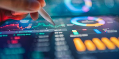 Hand interacting with a digital screen displaying colorful financial charts and graphs.