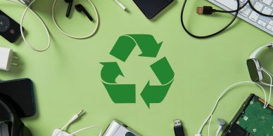 Electronic waste surrounding a recycling symbol.
