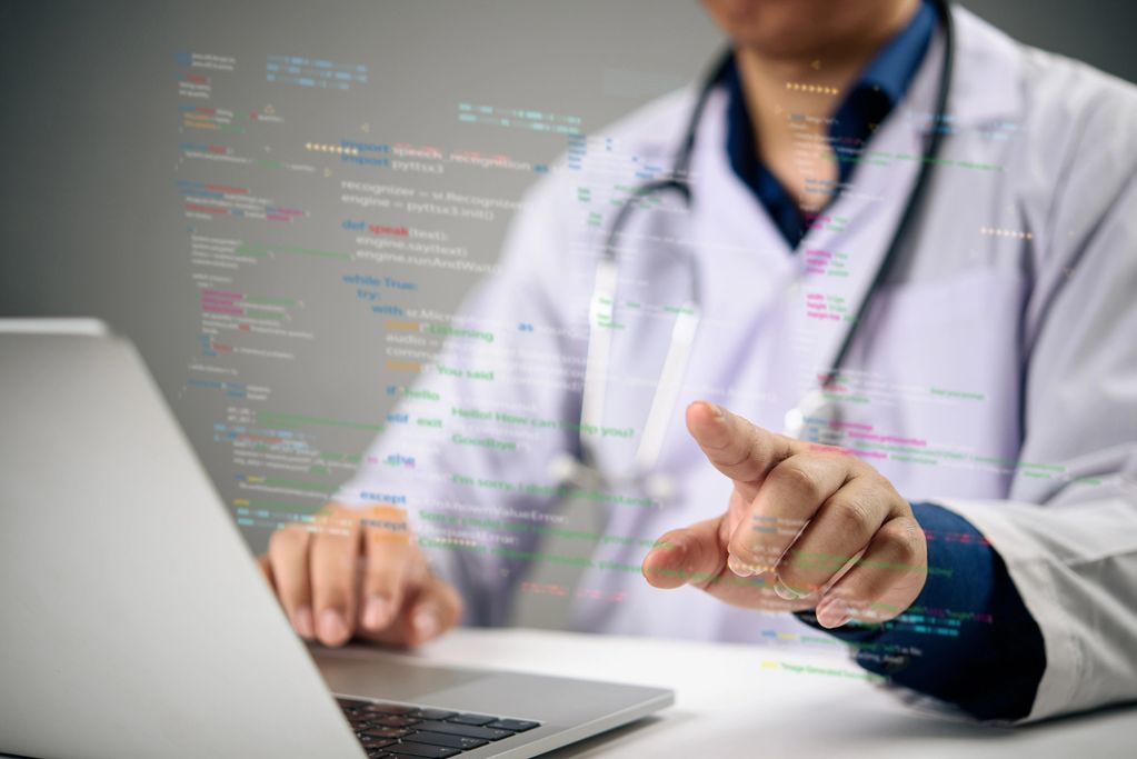 Doctor interacting with virtual code while using a laptop.