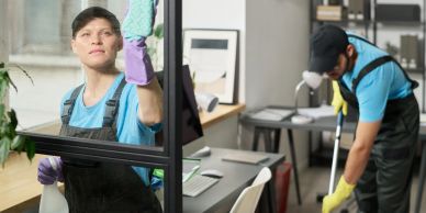 Two people cleaning a house, one washing glass and one mopping.