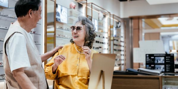 Elderly couple trying on glasses in an optical store.