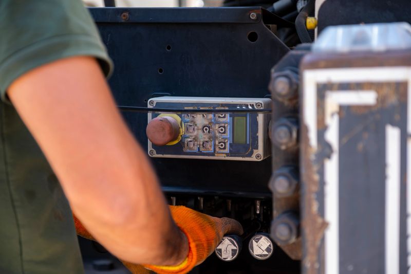 Worker's hands in protective gloves manipulating controls of industrial equipment, symbolizing technical expertise, mechanical work, and industrial precision. Close-up detailed scene emphasizing the importance of technical safety in operations