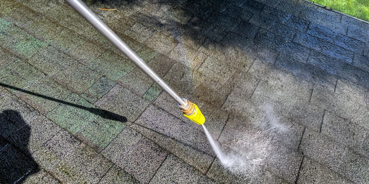 A pressure washer cleaning a paved surface outdoors.