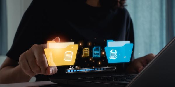 Person transferring digital files between folders on a laptop with a loading bar.