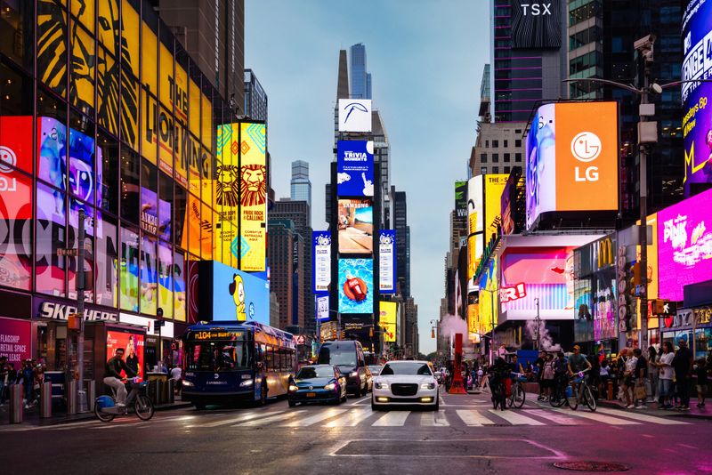 NYC Crowded Times Square in New York City at Twilight - Night in Summer. Zebra Crossing at Times Square with Cars, Buses waiting for Crowd of People crossing the famous iconic Broadway at Times Square District of Manhattan, New York City, USA