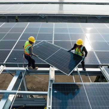 Two workers installing solar panels on a rooftop under clear conditions.