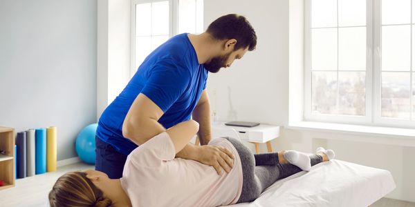Chiropractor performing a spinal adjustment on a patient lying on a treatment table.