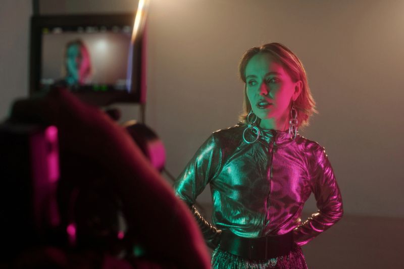 Waist up portrait of young woman as actress performing on set with camera filming, copy space
