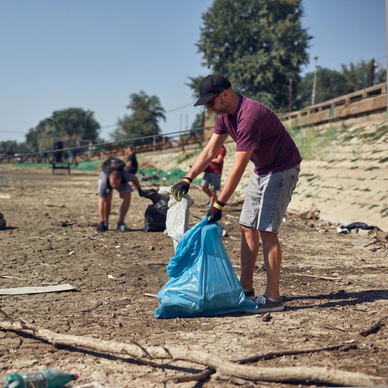 Environmental activist cleaning river shore from piled up trash.