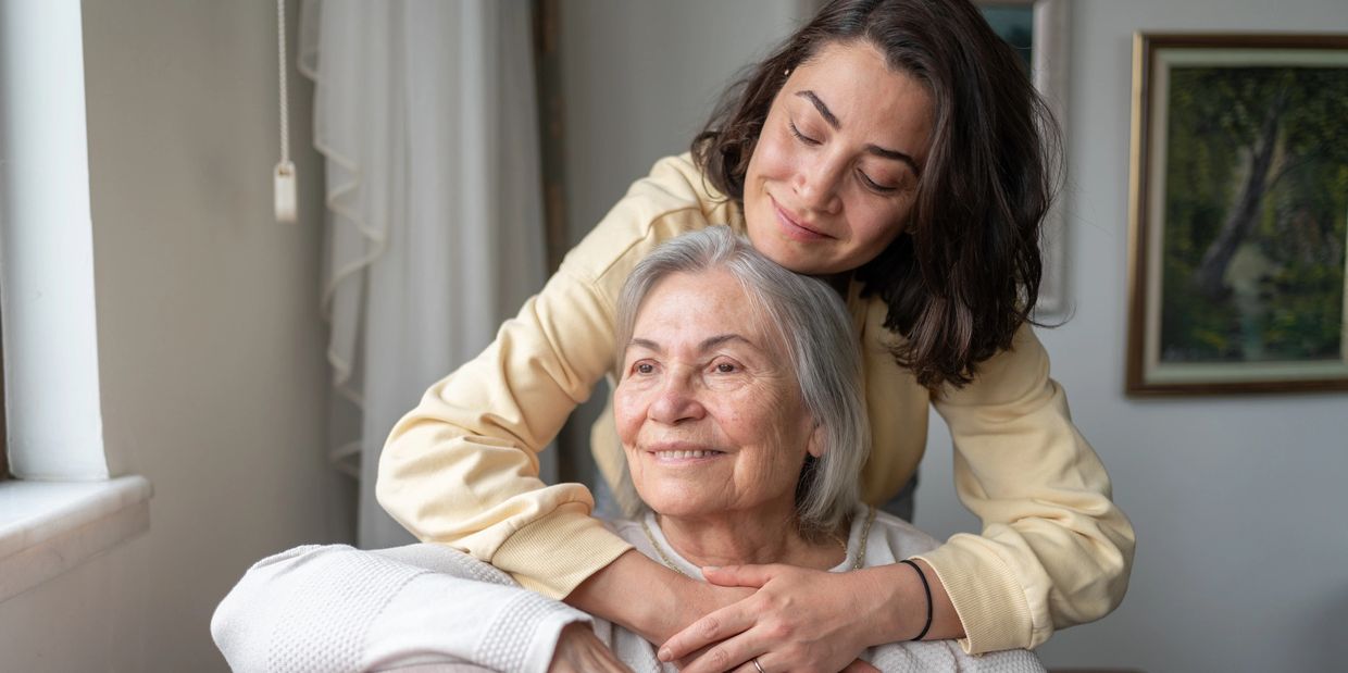 Mlajša ženska objema starejšo gospo na kavču
