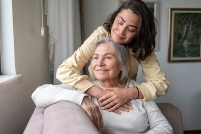 Young woman embracing elderly woman, both smiling.