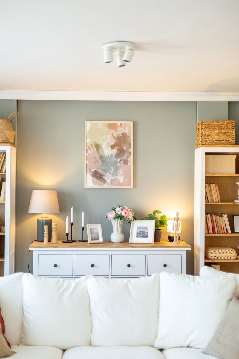 Cozy and stylish living room interior with white sofa, painting, flowers, and bookshelves