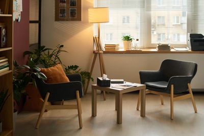 Photo of 2 chairs facing each other with a small table in the middle and a lamp behind them. 